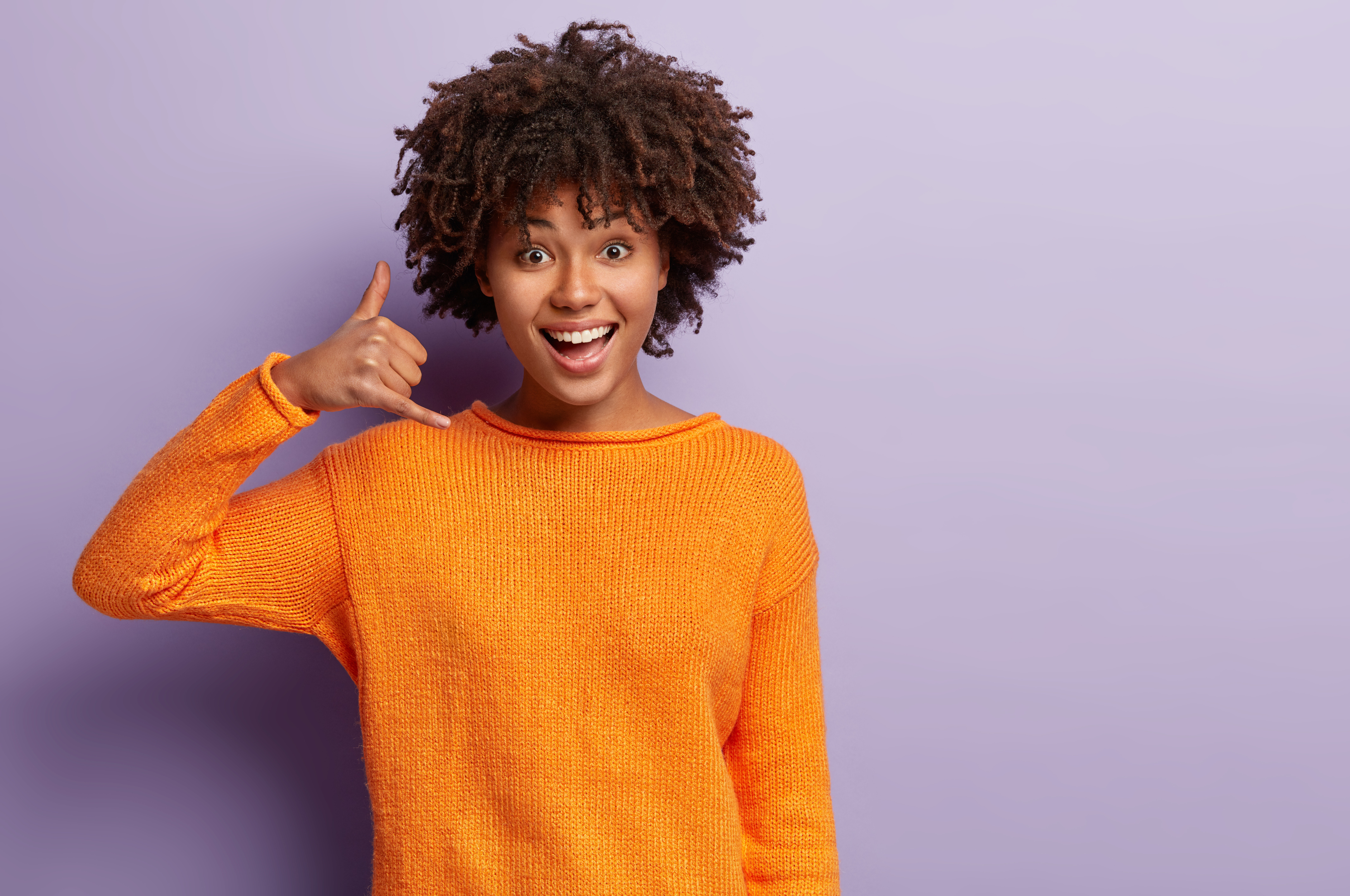 Woman miming a phone gesture.